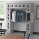 A Regency Space Solutions gray 3 tier locker with clothes hanging on it.