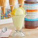 A glass of lemon ice cream with a spoon next to a bottle of LorAnn Lemon Custard Flavor Fountain syrup.