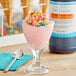 A glass of pink ice cream with LorAnn Fruity Cereal Milk syrup and candy on top.