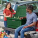 A man and woman sitting in the back of a truck next to a CaterGator Hunter Green cooler.