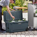 A man opening a CaterGator outdoor cooler to put bottles inside.