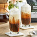A table with two glasses of Crown Beverages Organic Breakfast Blend coffee with whipped cream on top.
