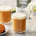 A glass mug of Crown Beverages Organic Breakfast Blend coffee with white foam.