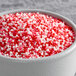 A bowl of red and white nonpareil sprinkles.