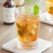 A glass of Woodford Reserve Mint Julep Syrup with a drink and mint leaves on a table.