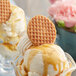Two Daelmans caramel waffle cookies on a table with ice cream.