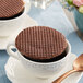 Two Daelmans chocolate wafers on a plate with a cup of coffee.