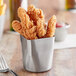A Tablecraft brushed stainless steel fry cup filled with fried chicken.