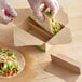 A person wearing plastic gloves putting a taco in a 4-compartment kraft taco holder insert.
