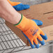 A person wearing Cordova orange and blue thermal gloves holding a box.