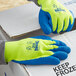 A gloved hand wearing a yellow and blue Cordova Therma-Viz terry thermal glove with blue crinkle latex palm coating.