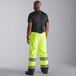 A man wearing Cordova hi-vis lime yellow quilted bib pants with reflective stripes.