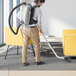 A man using an Atrix backpack vacuum to clean a room.