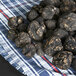 A pile of Urbani fresh small Burgundy truffles on a blue and white checkered cloth.