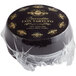 A black round Urbani Caciotta Truffle Cheese wrapped in plastic with gold text.