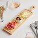 A Boska beech wood serving board with food on it on a table with wine.