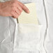 A hand holding a piece of paper and placing it in a pocket on a white Malt Impact ProMax lab coat.
