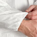 A person's hands button a white Malt Impact ProMax lab coat.
