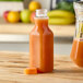 A 16 oz. Square Carafe PET Clear Juice Bottle of orange juice with a cap on a counter.