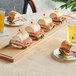 A group of sandwiches on a Boska beech wood serving board with glasses of beer.