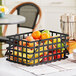 A black rectangular basket with oranges on a table.