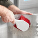 A person using a Lavex red utility brush to clean a bowl.