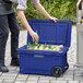 A man putting bottles into a CaterGator navy outdoor cooler.