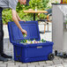 A man putting a can of beer into a navy CaterGator outdoor cooler filled with bottles.