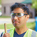 A man wearing Honeywell Uvex safety glasses with gray frames and indoor/outdoor lenses holding a pipe.