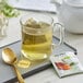 A glass mug of Bigelow Benefits Turmeric Chili Matcha tea with a tea bag in it.