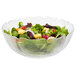 A clear Arcoroc glass bowl filled with salad greens, croutons, and vegetables.