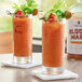 Two glasses of Top Hat Provisions Bloody Mary Mix garnished with vegetables on a table.