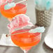 A pink drink with a Roses Dryden and Palmer cotton candy wrapped rock candy swizzle stick with blue and white candy floss.