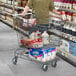 A man pushing a Regency Supermarket gray shopping cart in a grocery store aisle.