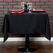 A table with a black Intedge cloth table cover and red plates on it.