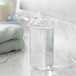 A clear PET Boston round bottle filled with liquid on a marble counter.