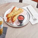 A Choice aluminum pizza pan with bread sticks and red sauce on a table.