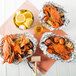 Three Chesapeake Crab Connection medium/large extra seasoned steamed blue crabs in aluminum foil containers with lemons.