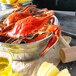 A bushel of live blue crabs on a table with lemons and a wooden hammer.