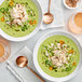 A group of bowls of green soup with Chesapeake Crab Connection jumbo lump crab meat and vegetables.