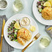 A white plate of Chesapeake Crab Connection Blue Crab Cake with lemons and a side of salad.