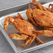 A metal tray of large and extra large seasoned steamed female Chesapeake crabs.