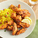 A plate of chicken wings and rice with lemon wedges seasoned with Regal Cajun Wing Rub.
