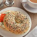 A bagel with cream cheese and tomatoes on a plate.