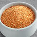 A bowl of orange seasoning powder on a table.