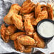 A bowl of chicken wings seasoned with Regal Spicy BBQ Wing Rub with a bowl of white sauce.