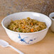 A blue Thunder Group Blue Bamboo melamine bowl filled with rice and vegetables with a spoon.