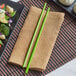 A plate of broccoli, rice, and vegetables with Emperor's Select green melamine chopsticks on a mat.