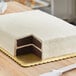 A cake with two layers cut in half on a gold double-wall laminated corrugated half sheet cake board.