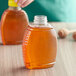 A close-up of a 16 oz. Queenline PET honey bottle on a table with a lid.